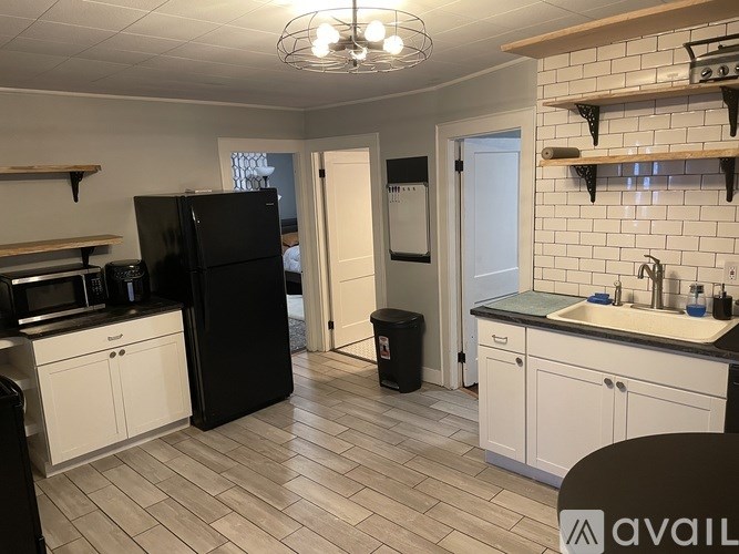 A kitchen with black appliances and white cabinets.