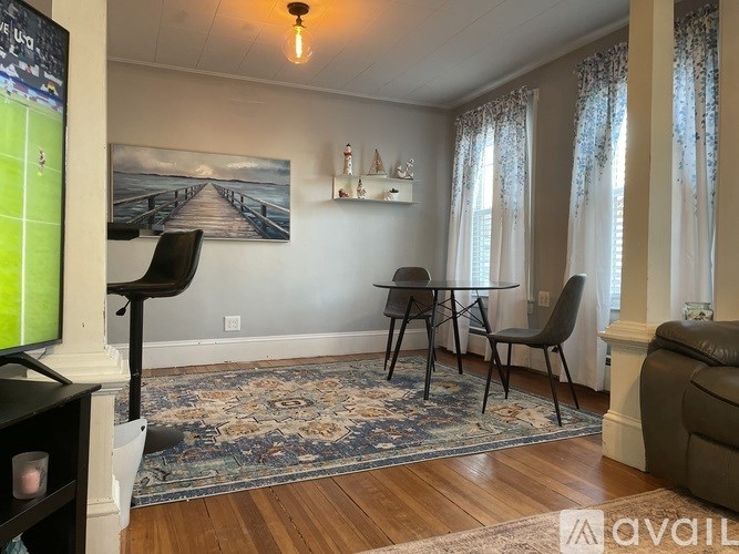 A living room with a TV, a sofa, a table and chairs.