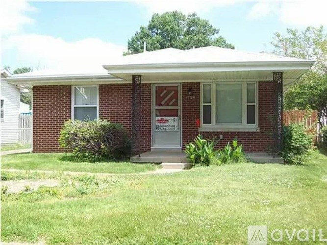 A red brick house with a white door and a sign that says "For Sale".