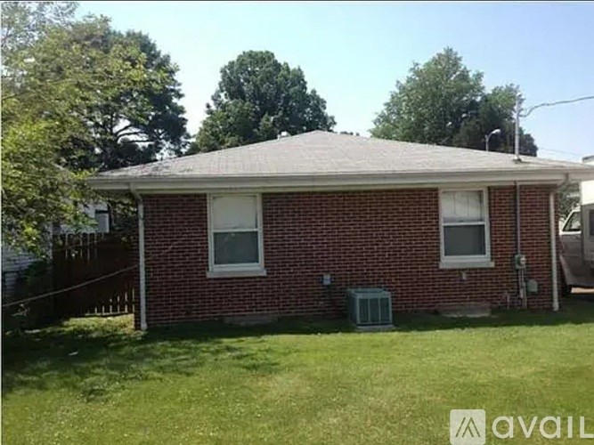 A red brick house with a white window and a grey roof.