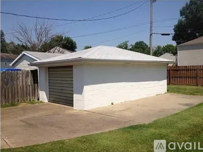 A small white house with a grey roof and a grey garage door.