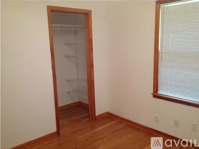 A room with a wooden floor and a white wall with a door and a window.