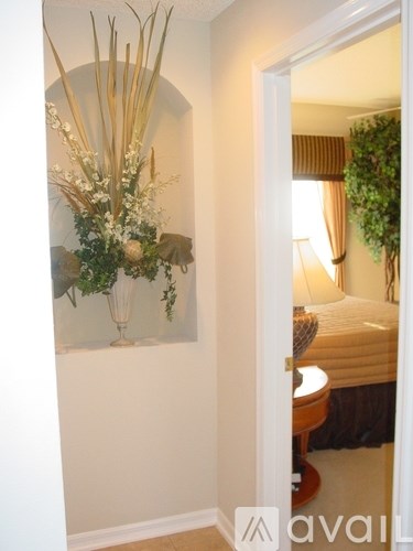 A bedroom with a bed, a lamp, and a plant.