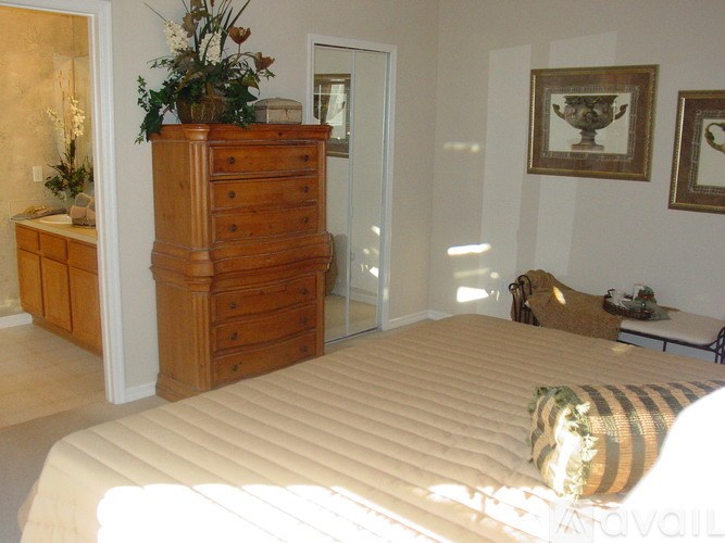 A bedroom with a large bed and a wooden chest of drawers.