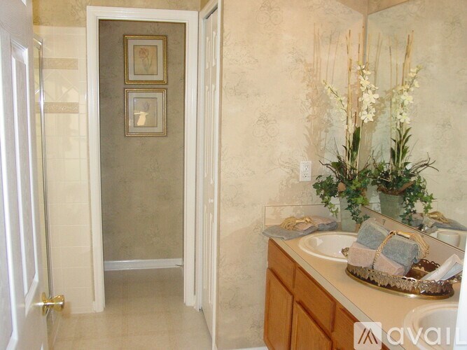 A bathroom with a sink, mirror, and a vase of flowers.