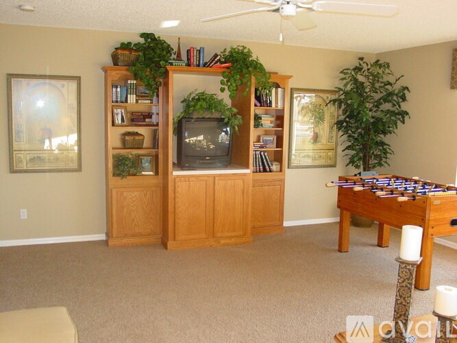 A living room with a television, bookshelf, and a pool table.