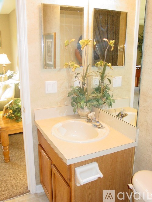 A bathroom with a sink, mirror, and a vase of flowers.