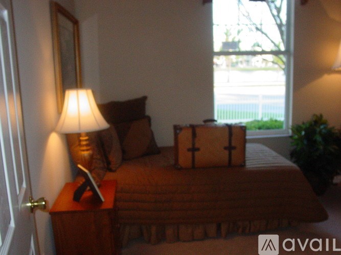 A bedroom with a bed, a lamp, and a window.