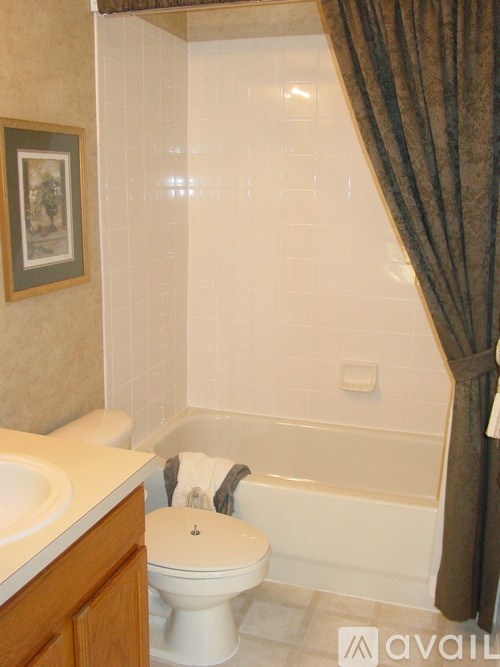 A white toilet sits in a bathroom next to a bathtub.
