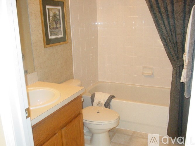 A white toilet sits in a bathroom next to a bathtub.