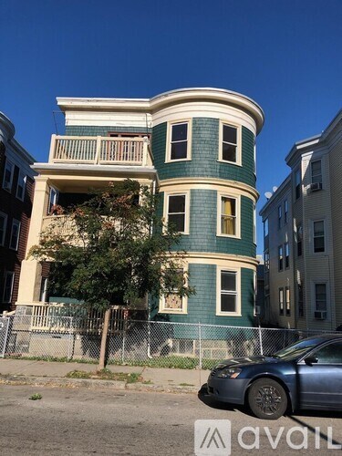 A blue car is parked in front of a green and white building.