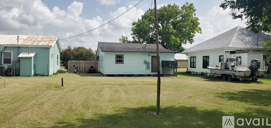 A grassy field with a blue house and a white trailer.