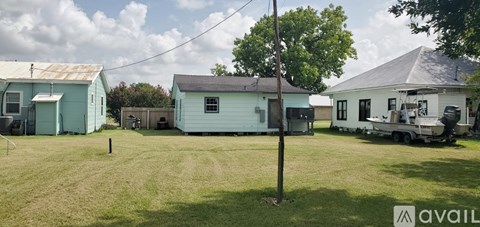 A grassy field with a blue house and a white trailer.