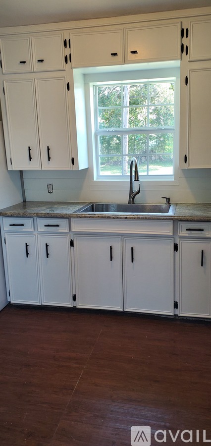 A kitchen with white cabinets and a window.