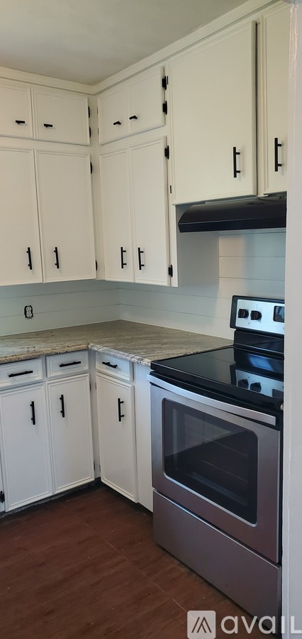 A kitchen with white cabinets and a black countertop.