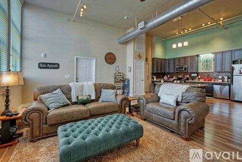 A living room with a green tufted ottoman in the center.