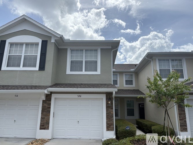 A two-story house with a white garage door and a tree in front.