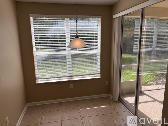 A room with a window covered in blinds and a light hanging from the ceiling.