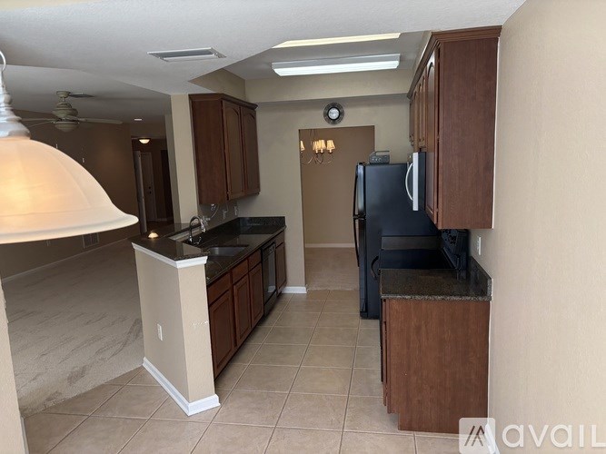A kitchen with a black fridge and brown cabinets.