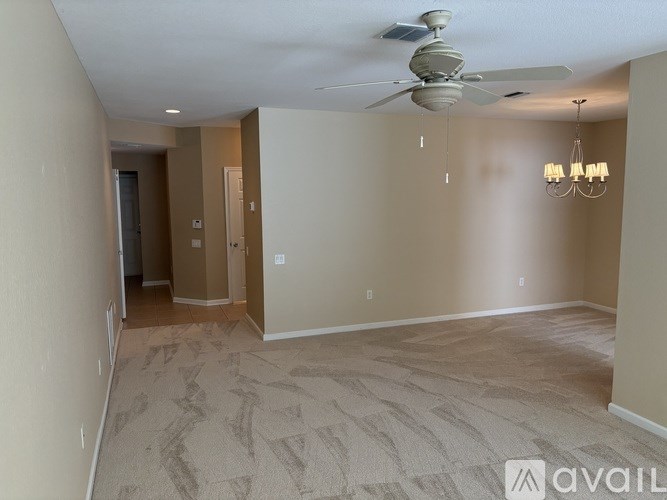 A room with a carpeted floor and a ceiling fan.