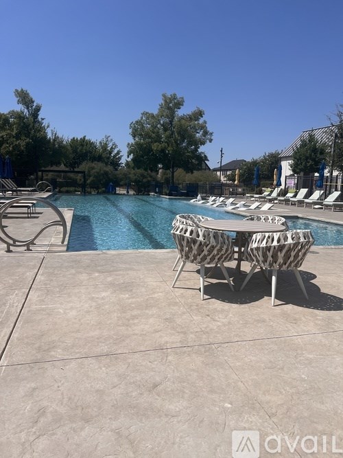 A pool with chairs around it and trees in the background.
