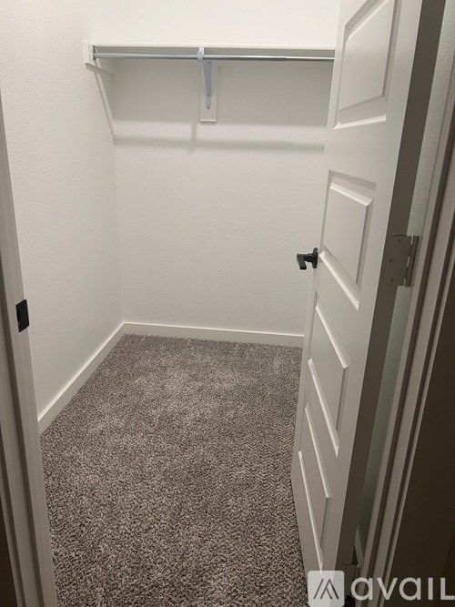 A small, empty room with a carpeted floor and a white door.