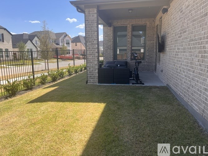 A backyard with a lawn and a house with a brick wall.