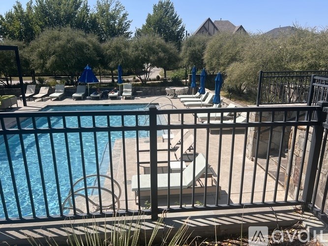 A pool with a black fence and a blue umbrella.