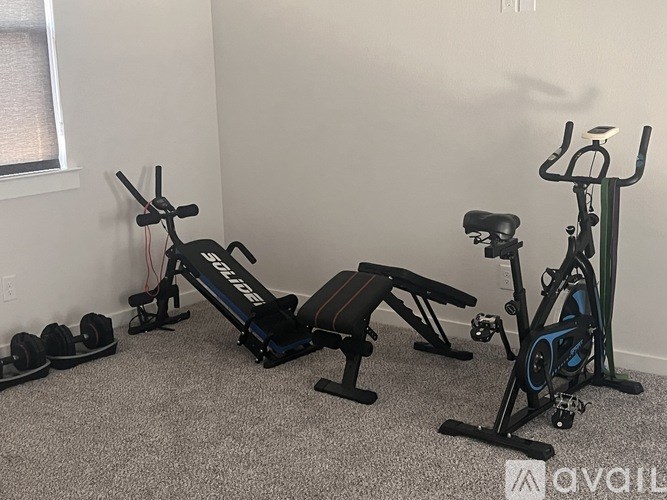 A room with a row of exercise equipment including a stationary bike and a rowing machine.