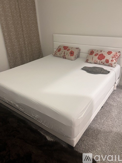 A white bed with a grey pillow and a grey blanket.