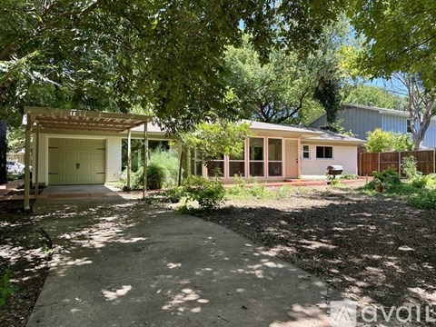A house with a garage is surrounded by trees.
