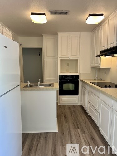 A kitchen with white cabinets and a white fridge.
