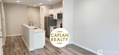 A kitchen area with a white island and a refrigerator in a property available for rent.