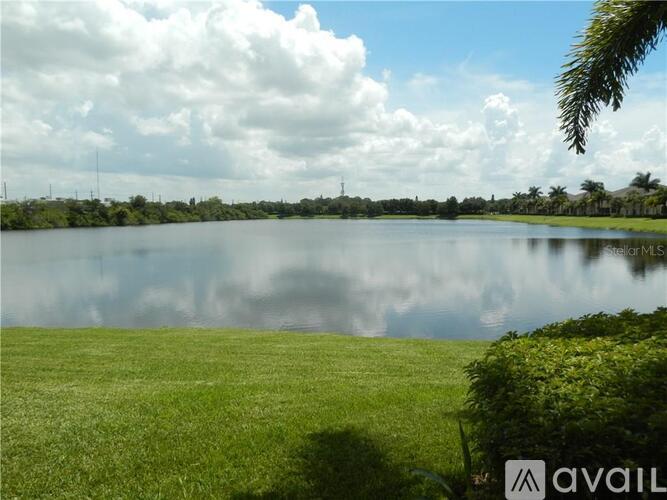 A large body of water surrounded by green grass under a cloudy sky.