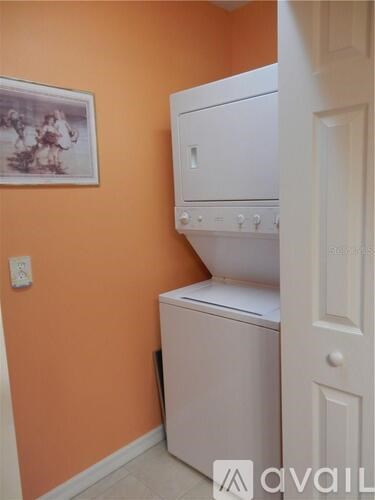 A white dishwasher is in a kitchen with orange walls.