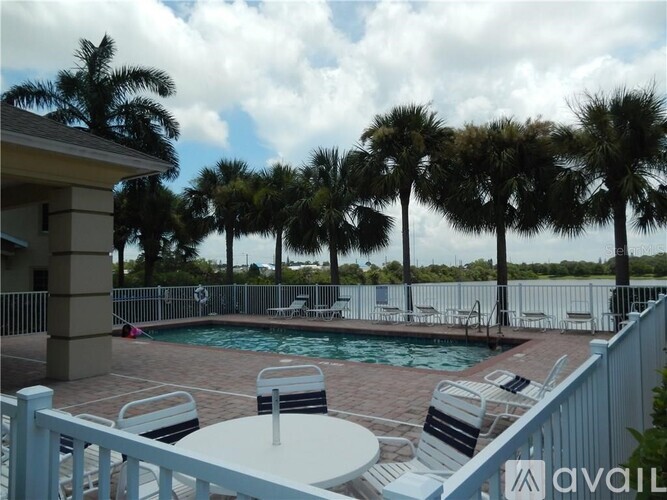 A pool surrounded by palm trees and deck chairs.