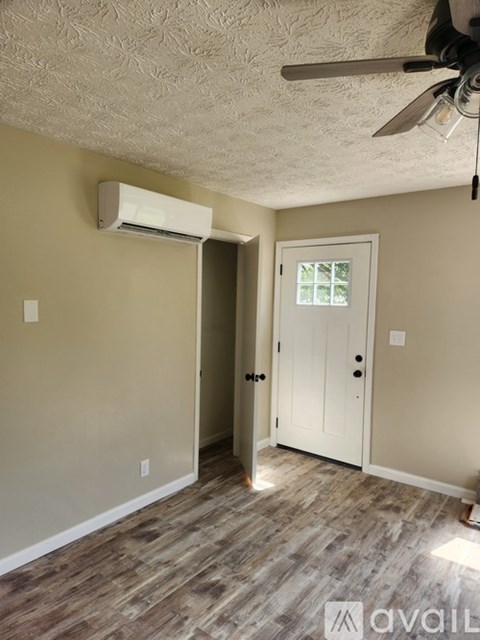 A room with a ceiling fan and a door leading to another room.