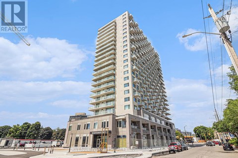 A tall residential building with a glass facade stands in front of a construction site.