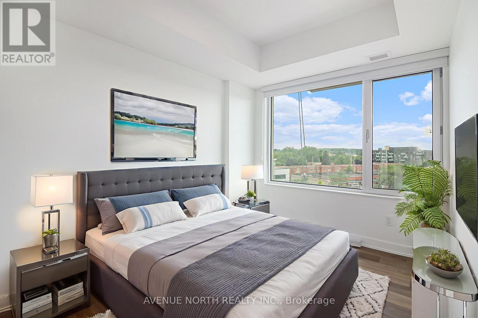 A well-lit bedroom with a large bed and a view of the outdoors through the window.