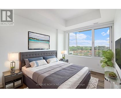 A well-lit bedroom with a large bed and a view of the outdoors through the window.
