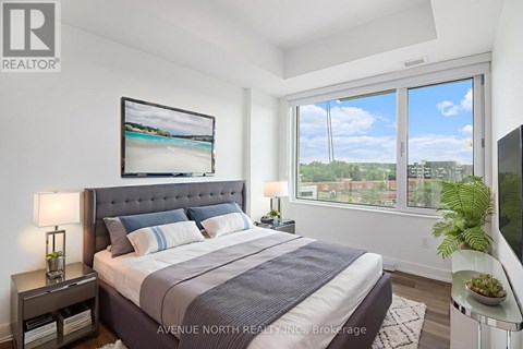 A well-lit bedroom with a large bed and a view of the outdoors through the window.