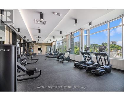 A gym with a row of treadmills and a row of stationary bikes.