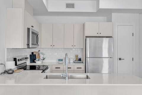 A modern kitchen with a stainless steel refrigerator and white cabinets.