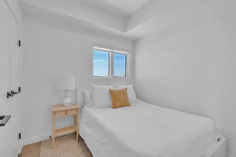 A bedroom with a bed, nightstand, and window.