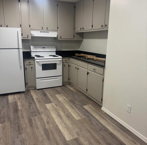 A kitchen with a white fridge, white stove, and white oven.