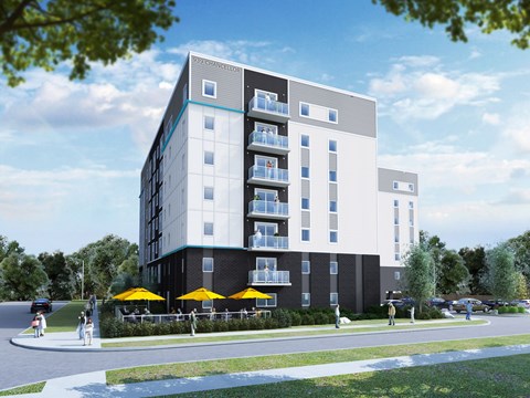 A modern apartment building with balconies and yellow umbrellas in front.