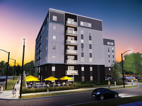 A modern apartment building with balconies and a parking lot in front.