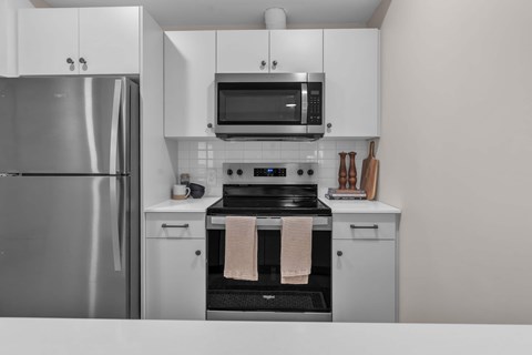 A modern kitchen with a stainless steel refrigerator, microwave, and oven.