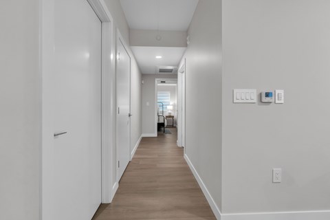 A long hallway with white walls and wood flooring.