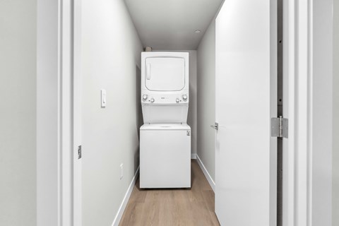 A white tankless water heater sits in a narrow hallway.